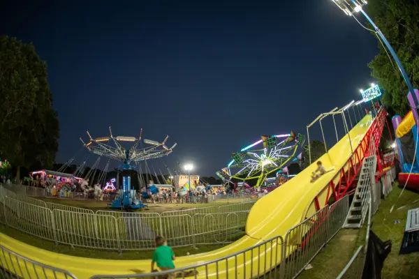 Yellow slide and spinning rides on the fair midway at dusk