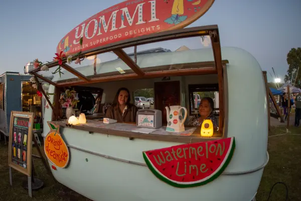 Yommi frozen treats camper serving fairgoers at dusk