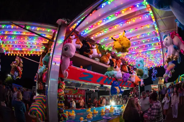 Duck pond game booth stacked with stuffed-animal prizes at night