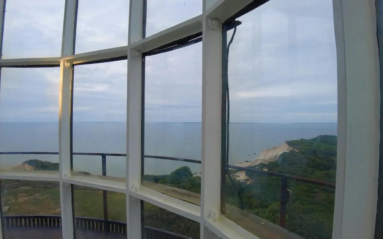View through the curved lantern-room windows at the top of Gay Head Lighthouse toward the cliffs and sea
