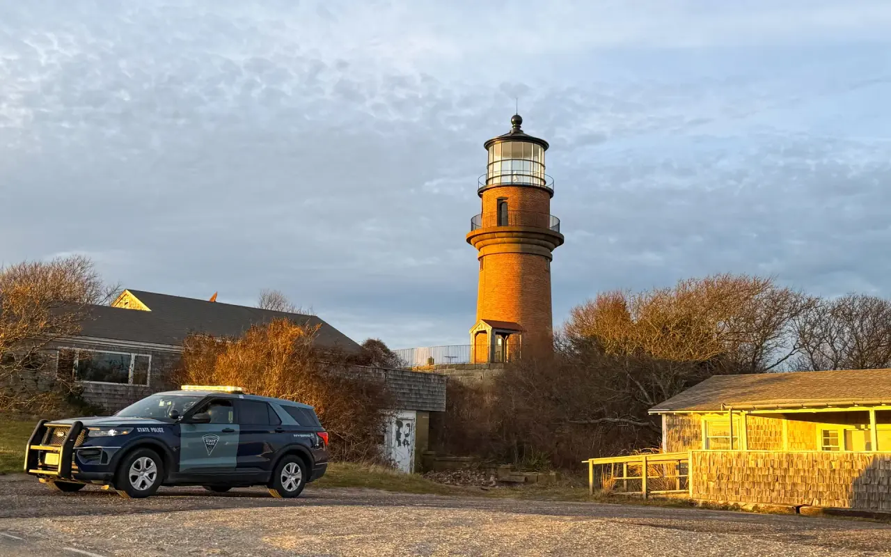 The red brick Gay Head Lighthouse rising above the low shop buildings at Aquinnah Circle in golden light
