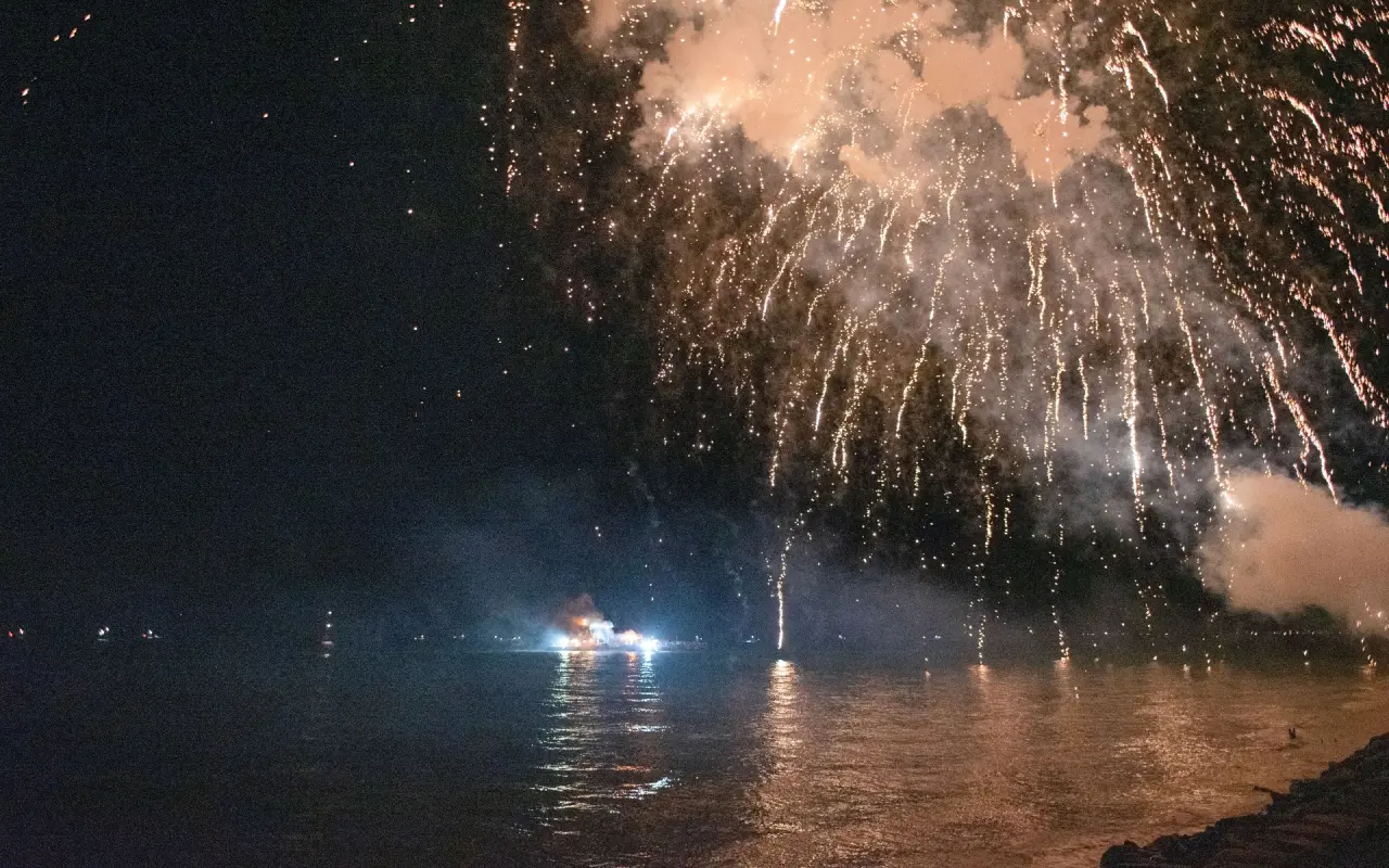 Fireworks bursting over dark water off Oak Bluffs with reflections