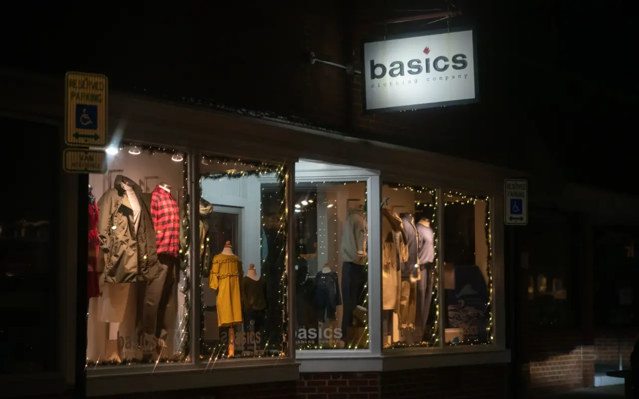 The illuminated storefront window of the Basics clothing store on Circuit Avenue in Oak Bluffs at night