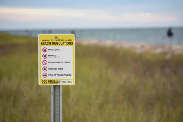 Joseph Sylvia State Beach regulations sign in the dune grass