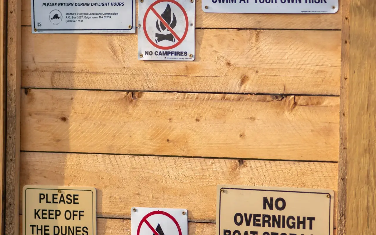 Cluster of small rule signs on a wooden wall at a beach entrance