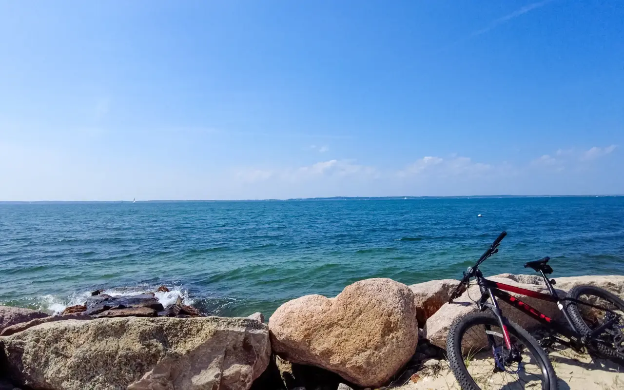 Bicycles propped against boulders beside blue water