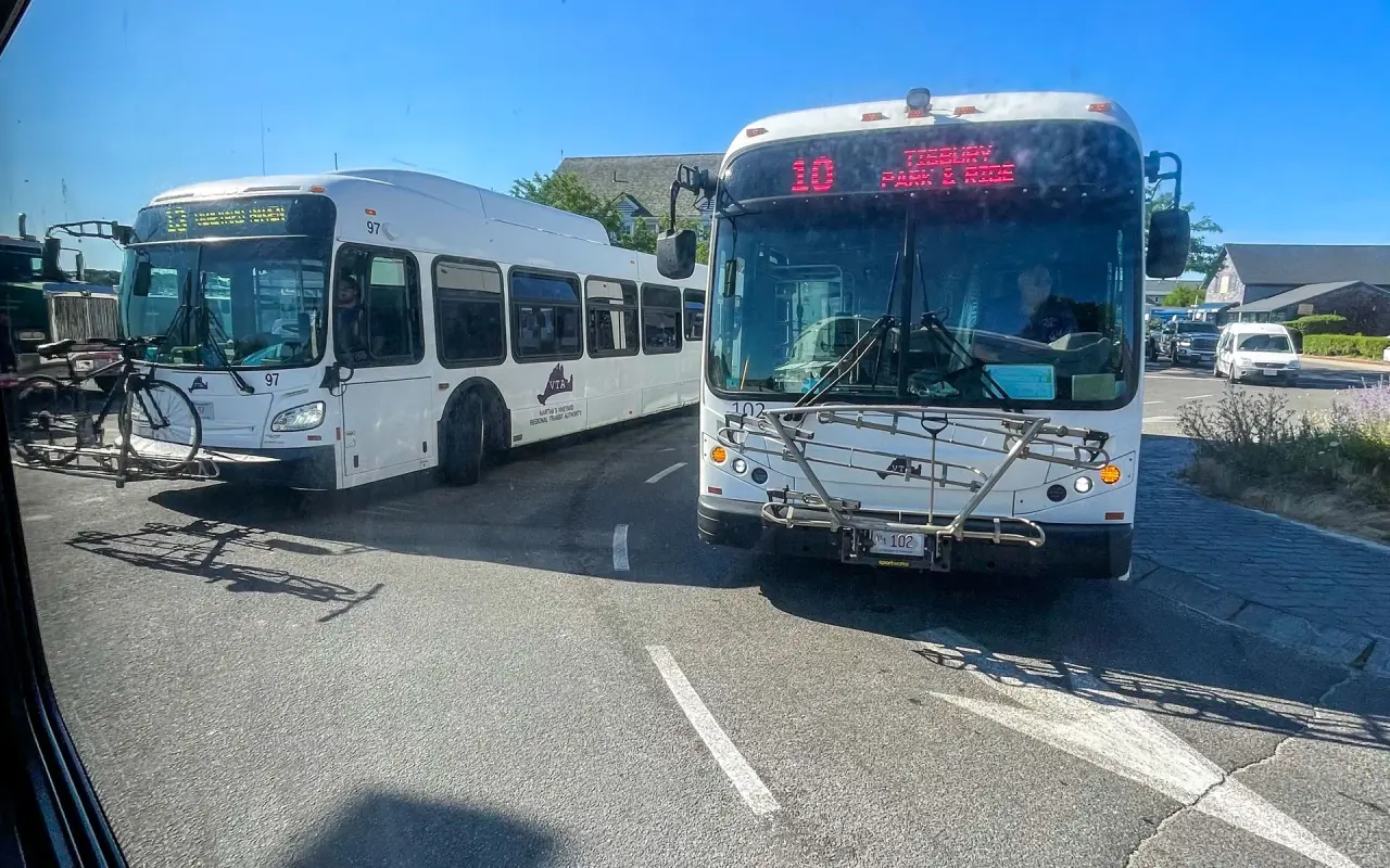 Two white VTA buses, routes 10 and 13, parked at the Vineyard Haven ferry terminal under a blue sky