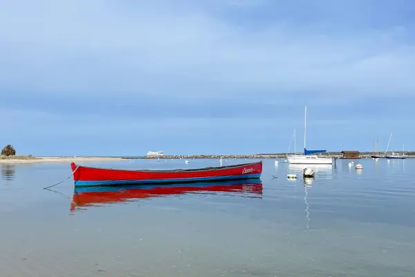 A red dinghy on still morning water