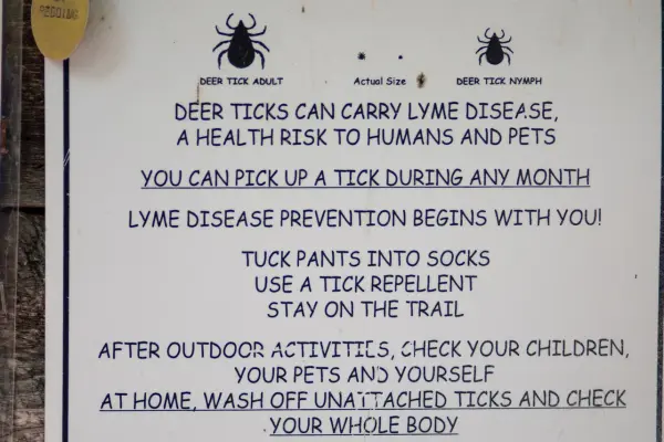 Deer tick warning sign with Lyme disease prevention tips