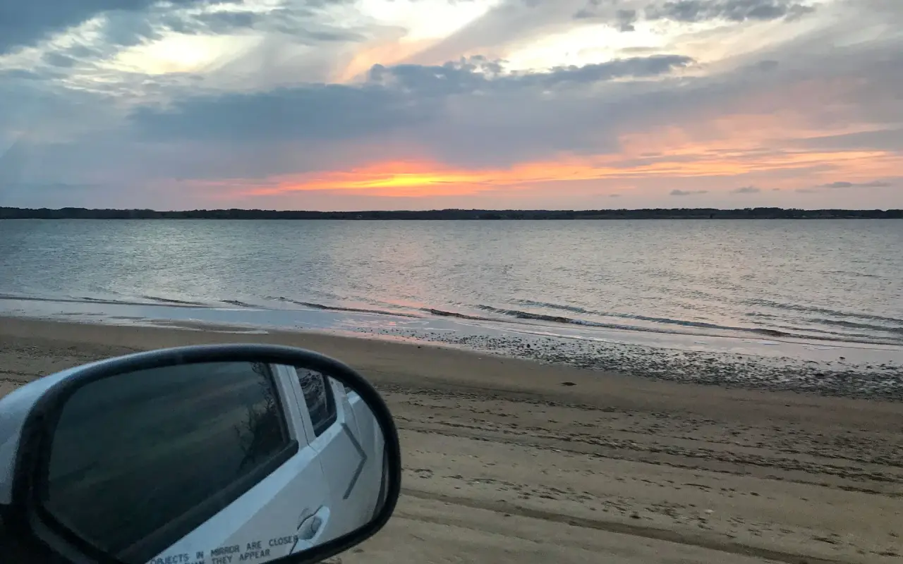 Sunset over the sand at East Beach on Chappaquiddick seen past a car mirror