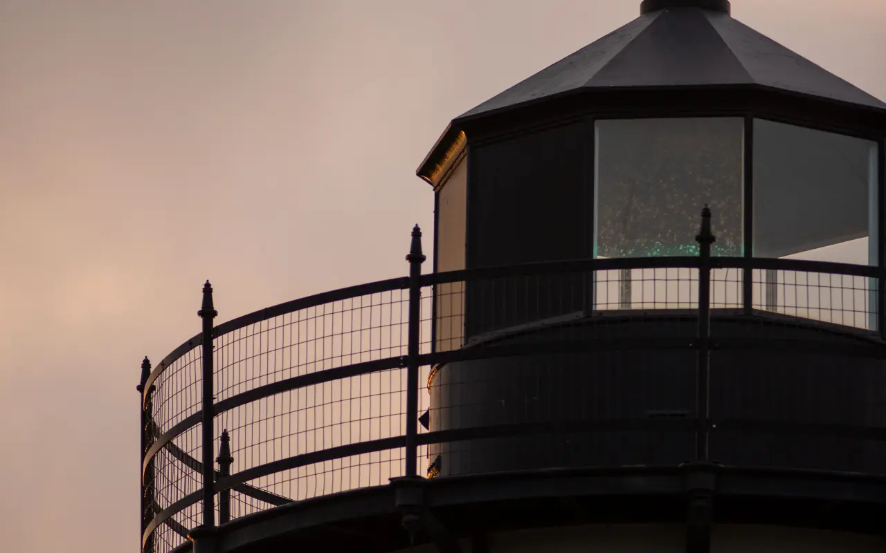 Lantern room of East Chop Lighthouse silhouetted against a dusk sky