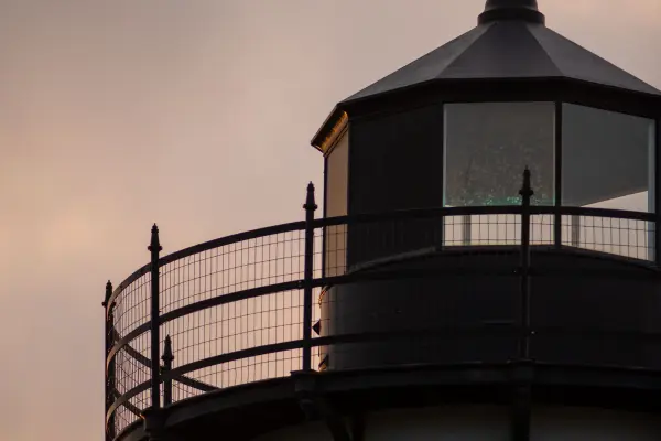 East Chop Lighthouse lantern silhouetted against a pink sunset sky