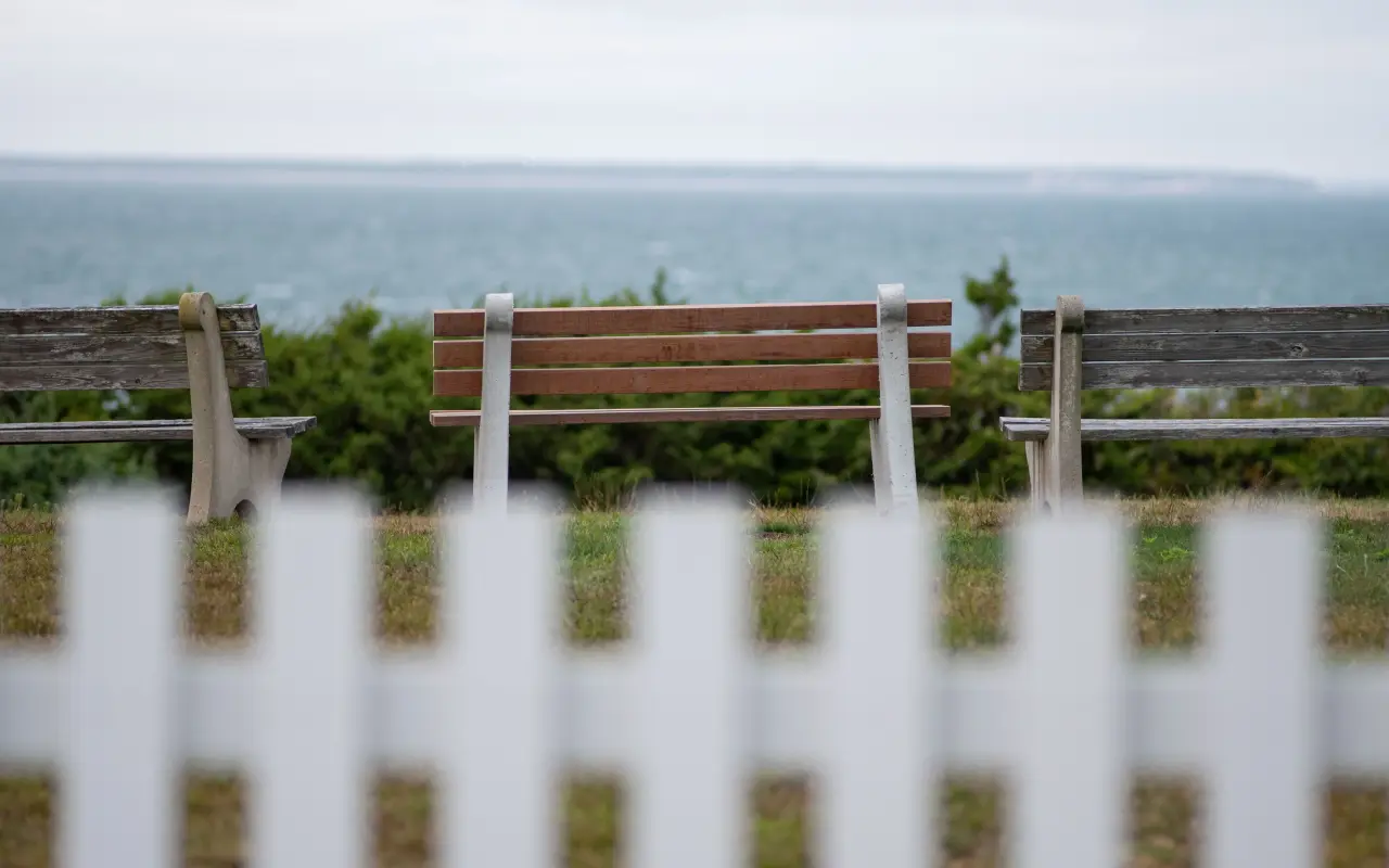 Benches behind a white picket fence overlooking the water at East Chop in Oak Bluffs