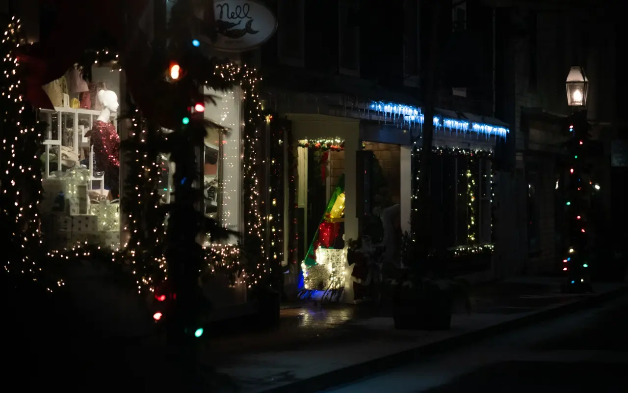 Edgartown shopfronts at night strung with colored holiday lights and a lit lamppost