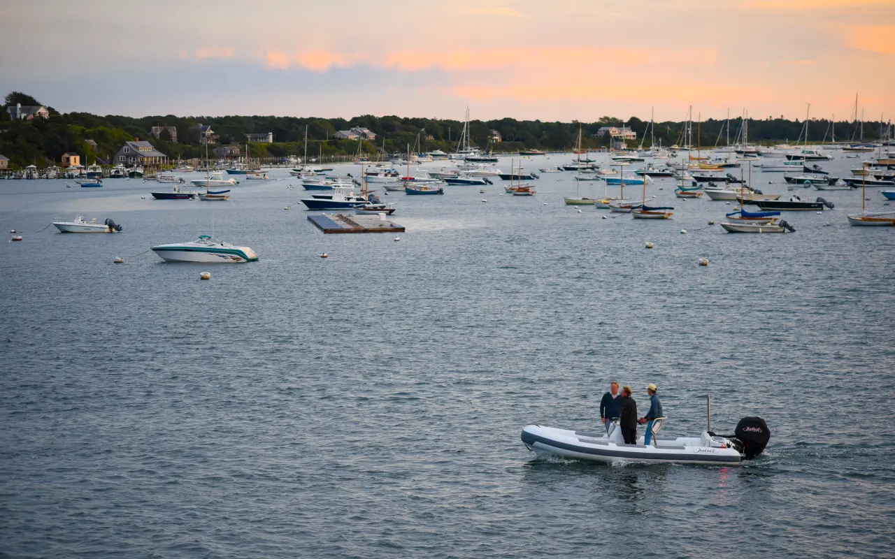 Boats on moorings in Edgartown harbor at sunset with a small launch in the foreground
