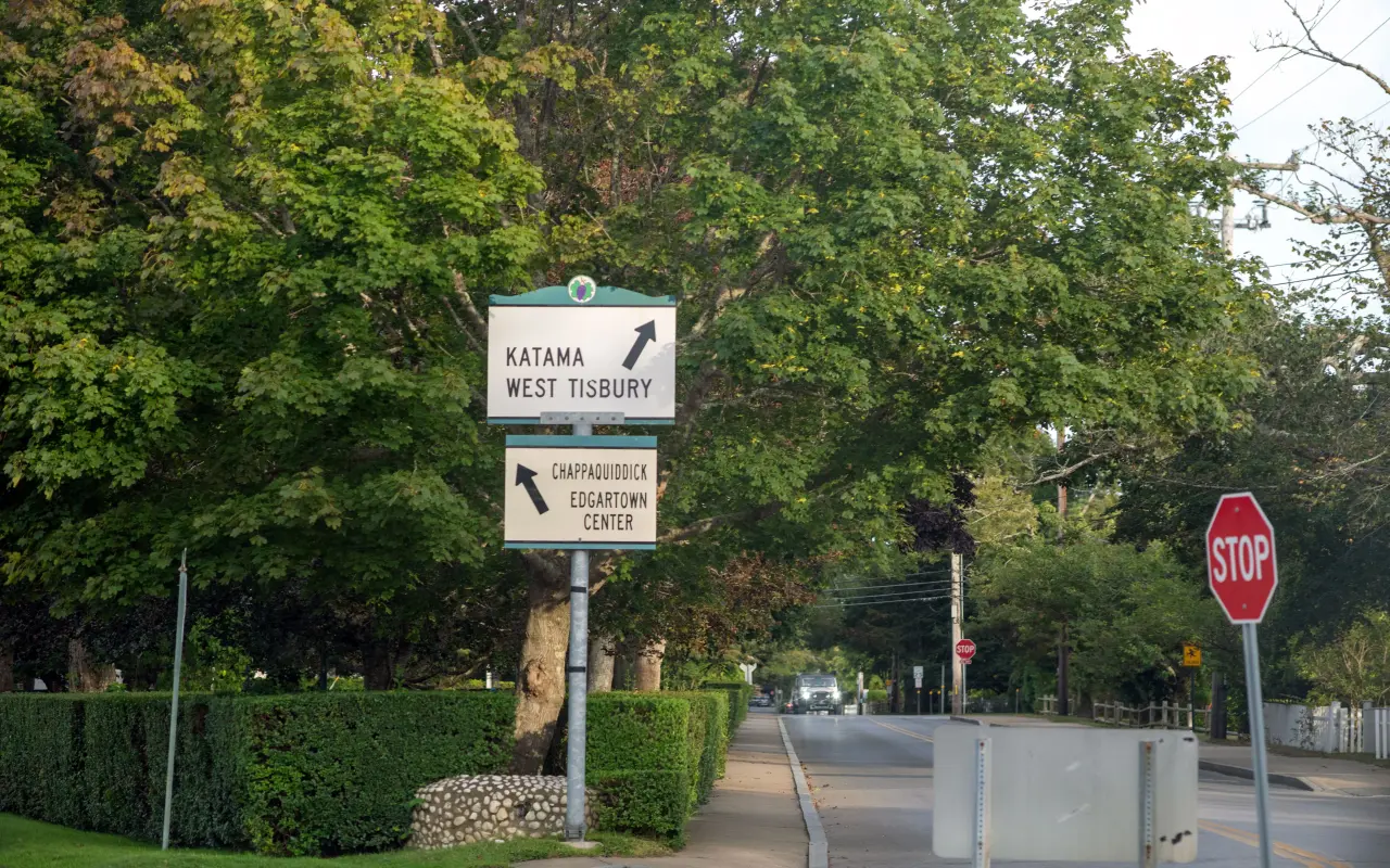 Green road signs at an intersection pointing to Katama and West Tisbury, and to Chappaquiddick and Edgartown Center, with a stop sign
