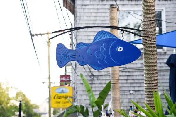 Carved blue wooden fish sign hanging outside a shop