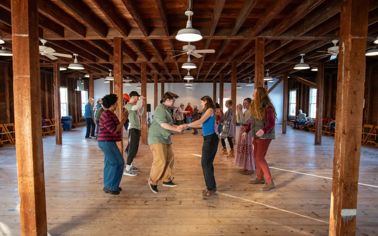 Dancers on the wooden floor of the Grange Hall in West Tisbury under exposed timber beams