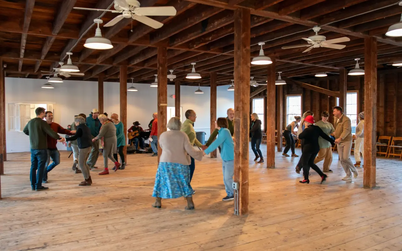 Dancers on the wooden floor of the Grange Hall in West Tisbury under exposed beams and ceiling fans