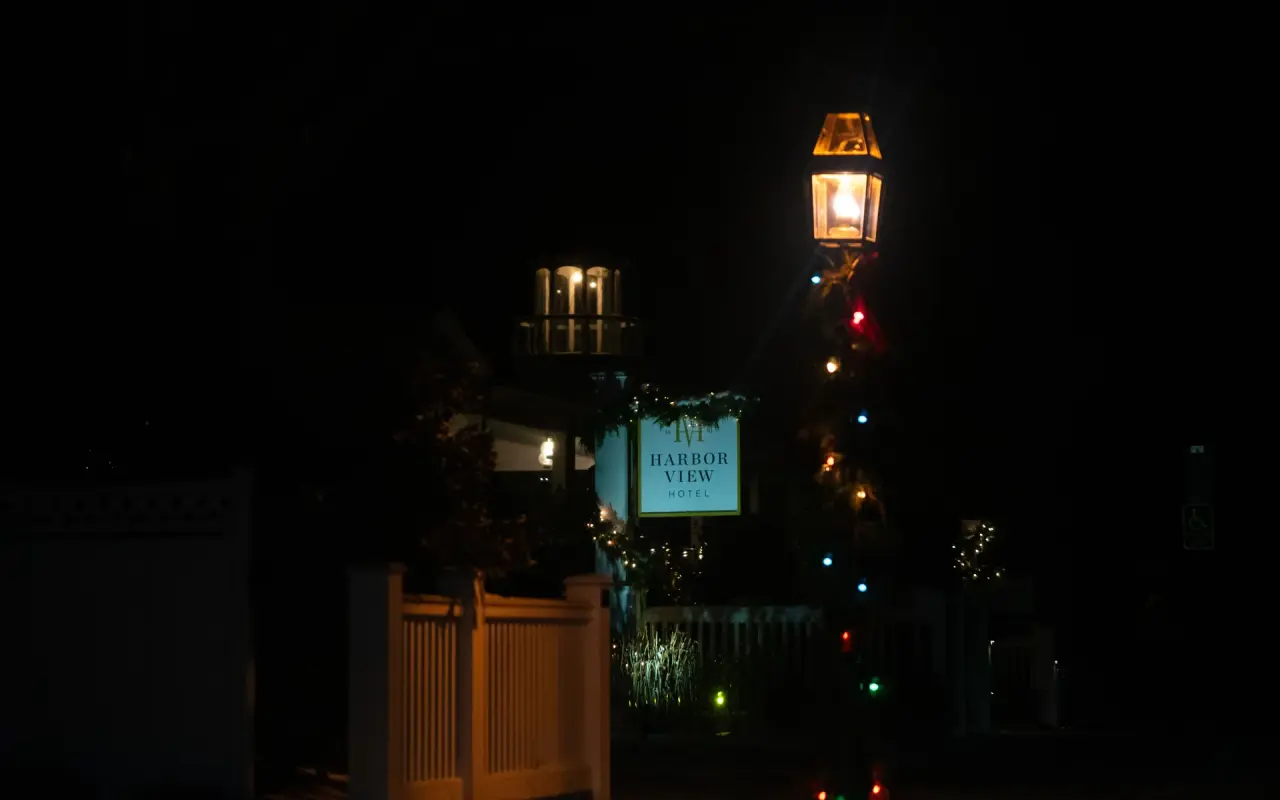 The lit Harbor View Hotel sign at night in Edgartown with holiday lights and a lamp above it