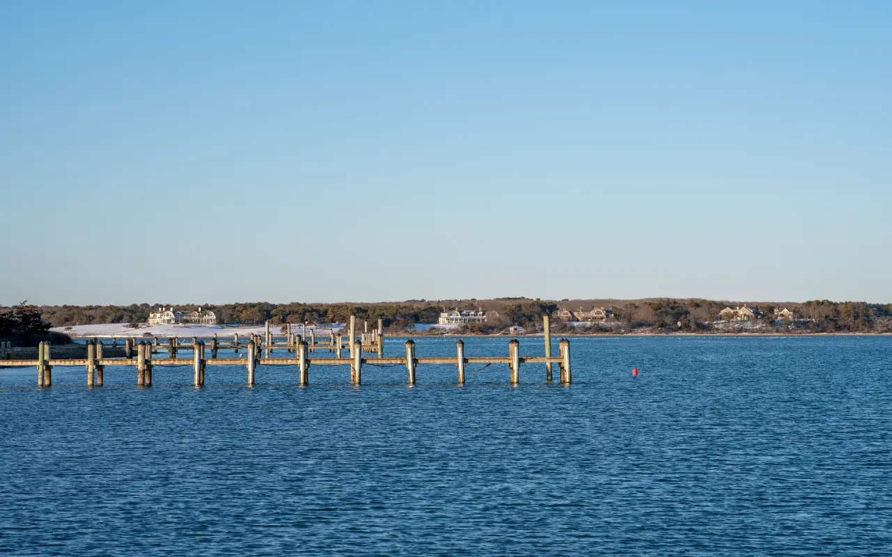 A wooden dock on Katama Bay in Edgartown on a clear cold day with blue water and bare shoreline