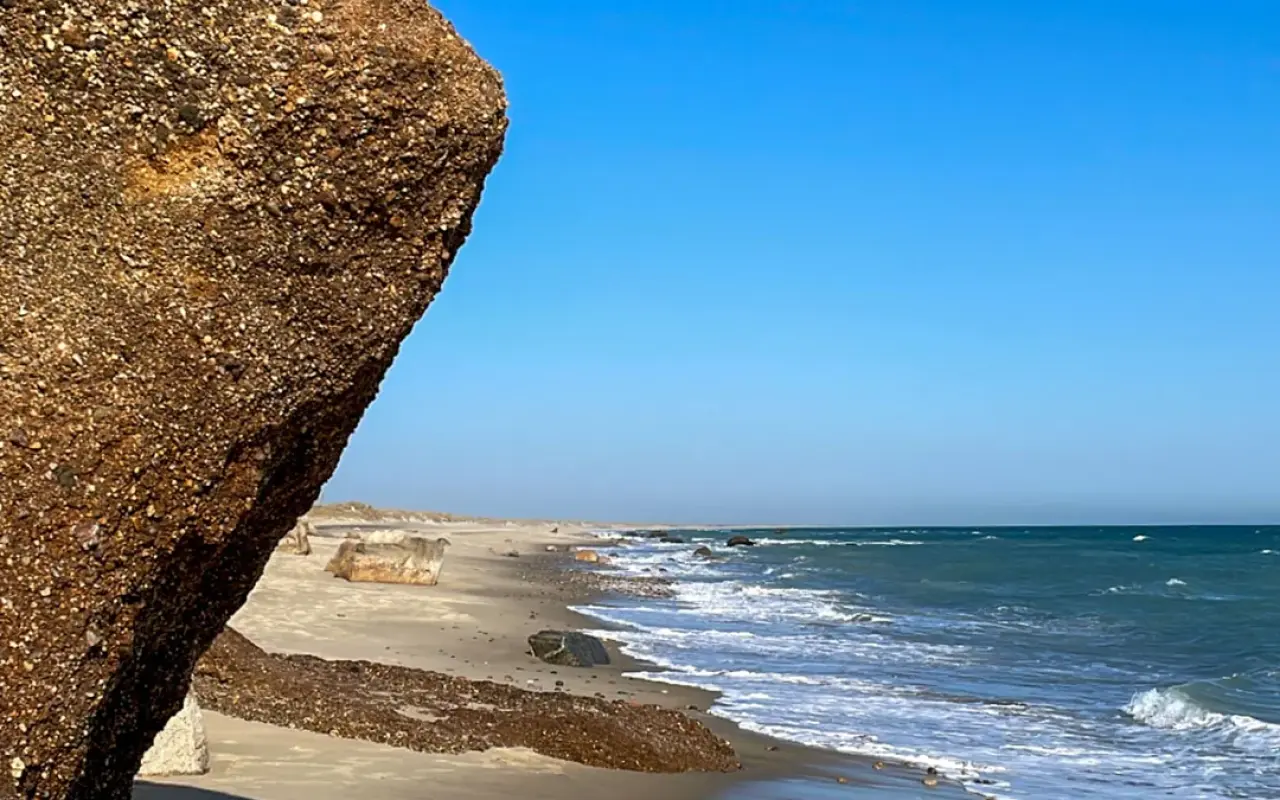 Lucy Vincent Beach in Chilmark with a clay boulder in the foreground and surf breaking along the sand