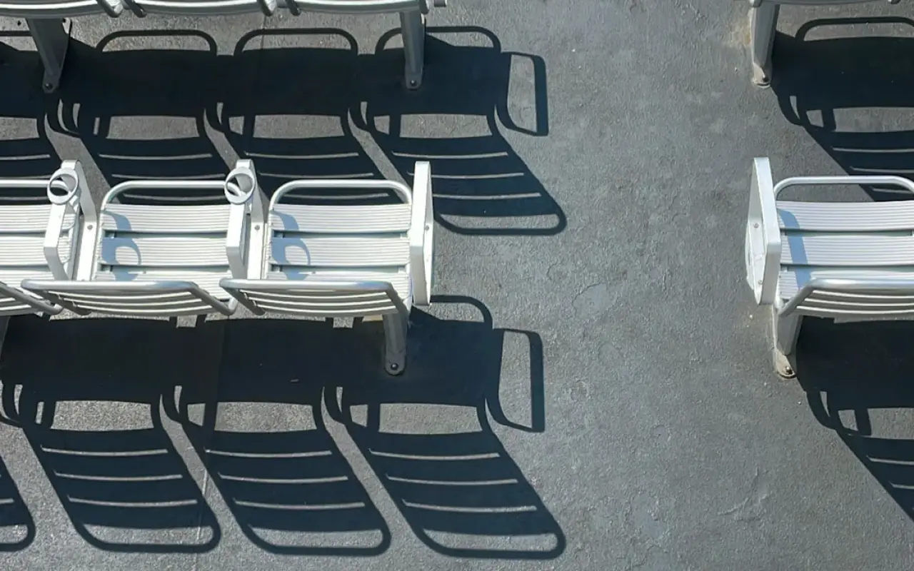 Rows of white deck chairs casting shadows on the upper deck of a ferry