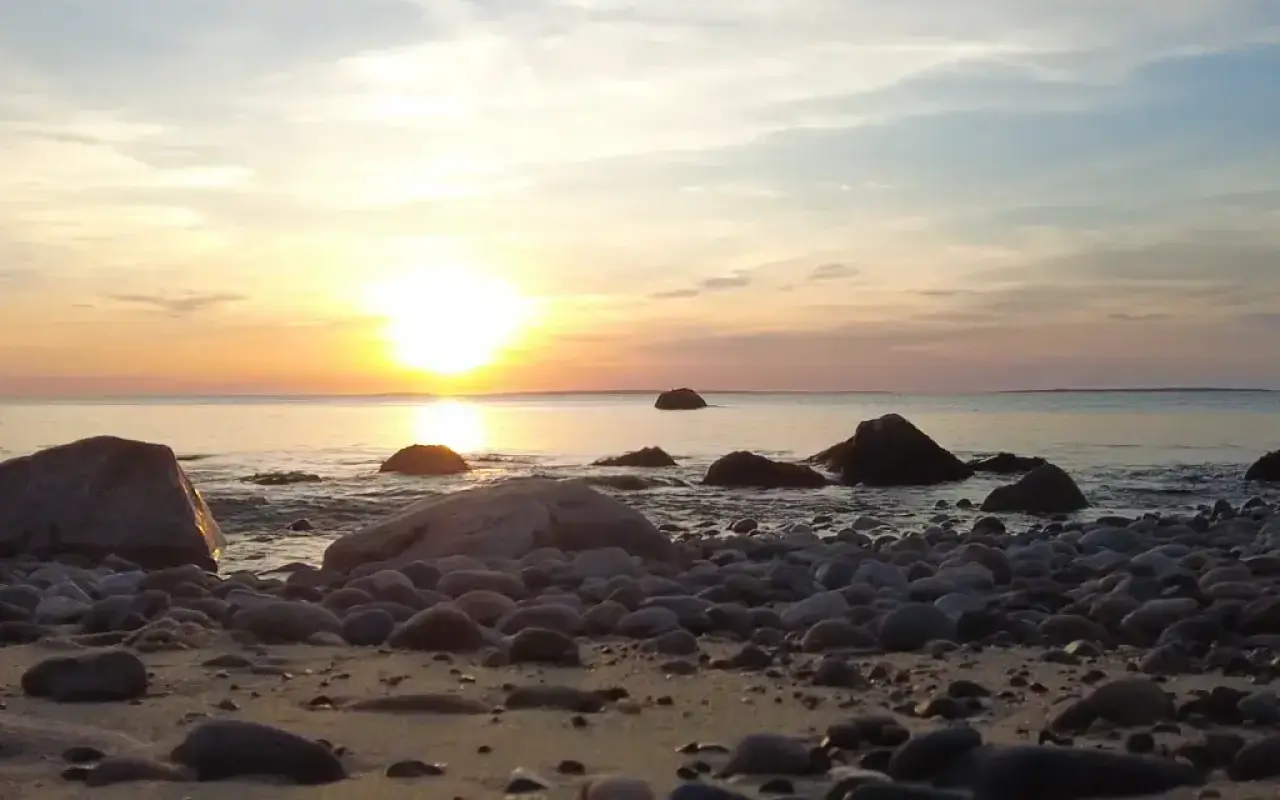 The sun setting over the water from the rocky north shore near Menemsha