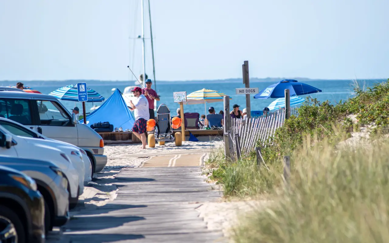 Cars parked at Menemsha Beach with beach umbrellas and the Sound beyond