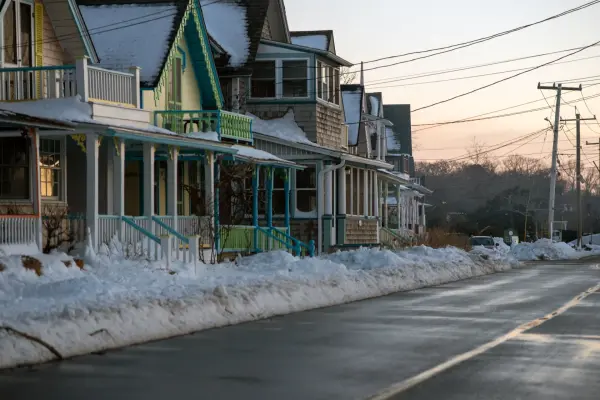 The same lane in winter: cottages shuttered, snow along the curb, the sky going pink