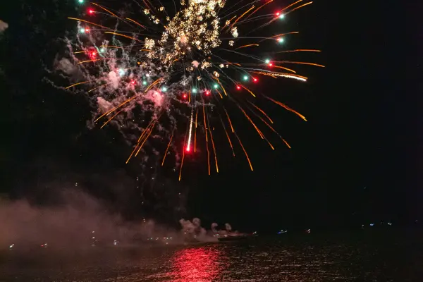 Red and green fireworks bursting over the water