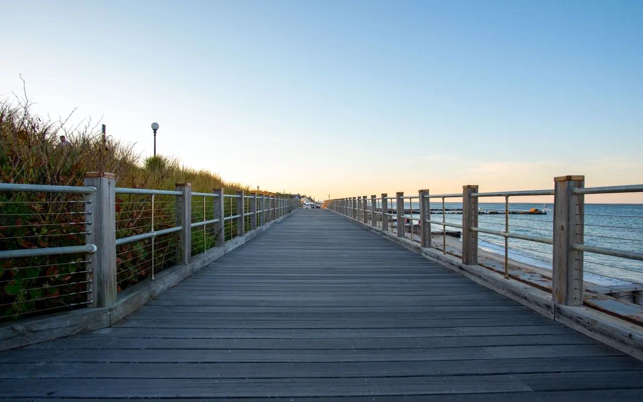 Wooden boardwalk with railings along the Oak Bluffs shore at dusk