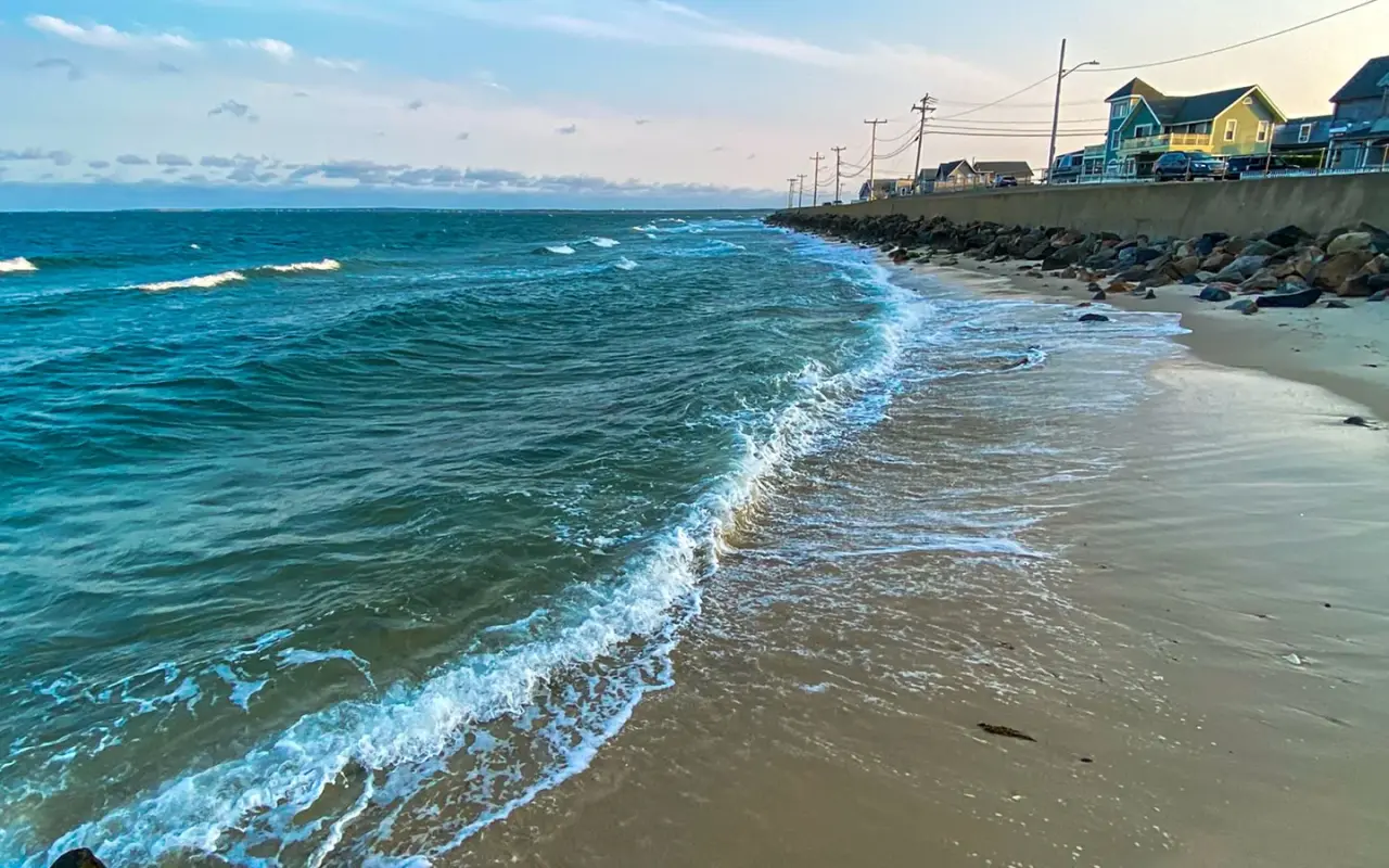 Small waves on Inkwell Beach at evening with the jetty and the Seaview Avenue rail