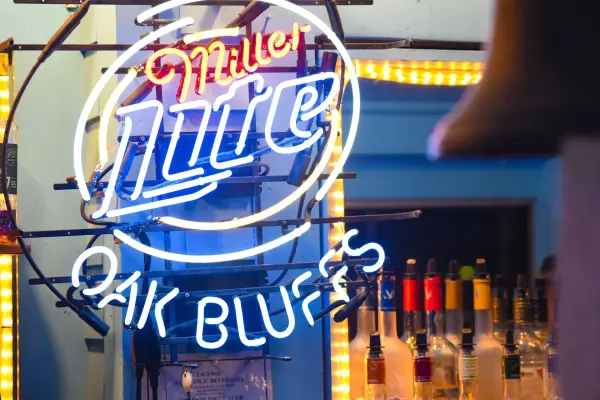 Miller Lite Oak Bluffs neon sign glowing behind the bar