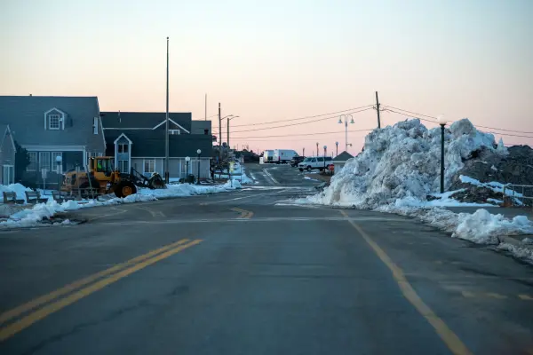 Towering plowed snow pile beside an Oak Bluffs street at dusk