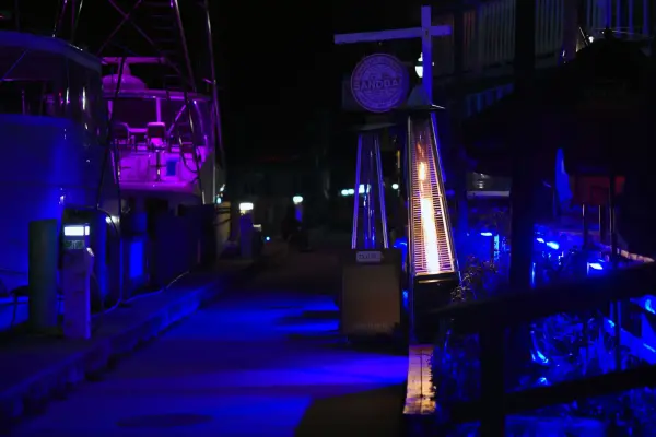 Harbor walkway glowing at night with patio heaters and boat lights