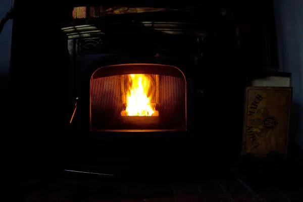 Fire glowing inside a wood stove in a dark room