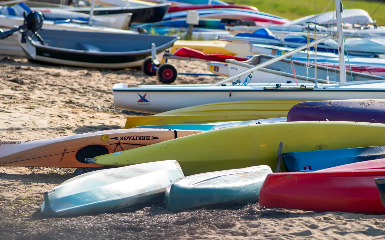Colorful kayaks and small boats pulled up on a sandy beach on Menemsha Pond
