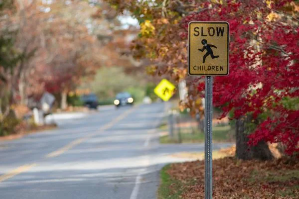 Slow Children sign on a tree-lined road in fall