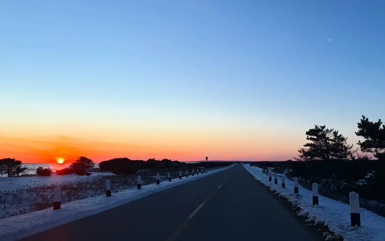 Straight road across the Katama plains at sunset with light snow along the edges