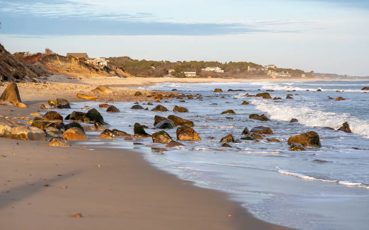 Golden light over the weed-covered boulders in the shallows at Squibnocket
