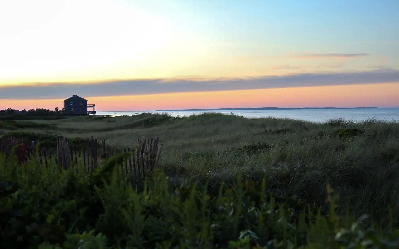 Sunset over Vineyard Sound seen across dune grass at Menemsha