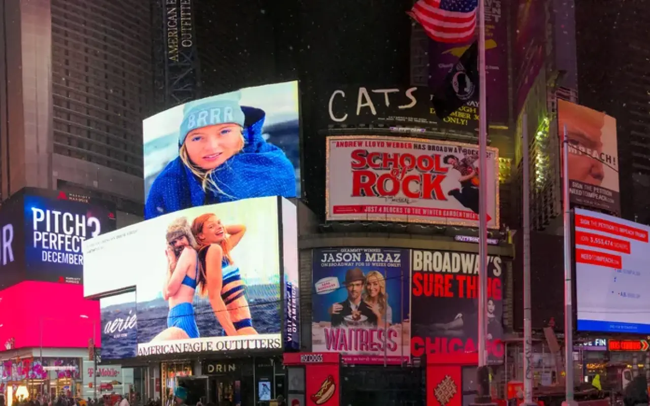 Times Square in New York at night with bright billboards for Broadway shows and crowds on the sidewalk