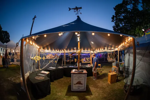 Tucker and Holland metal sculptors' tent glowing with weathervanes at dusk
