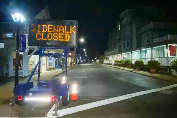 Sidewalk Closed sign on a downtown street at night