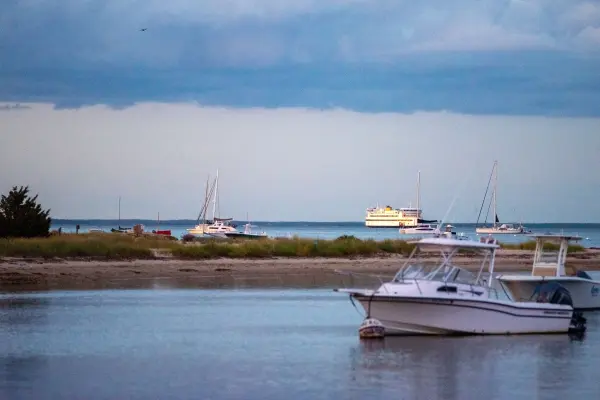 Boats anchored off the beach with a ferry in the distance