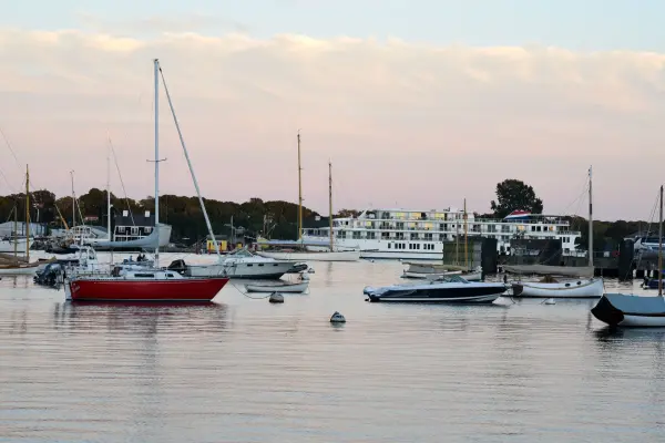 Boats moored in the harbor with a small cruise ship beyond