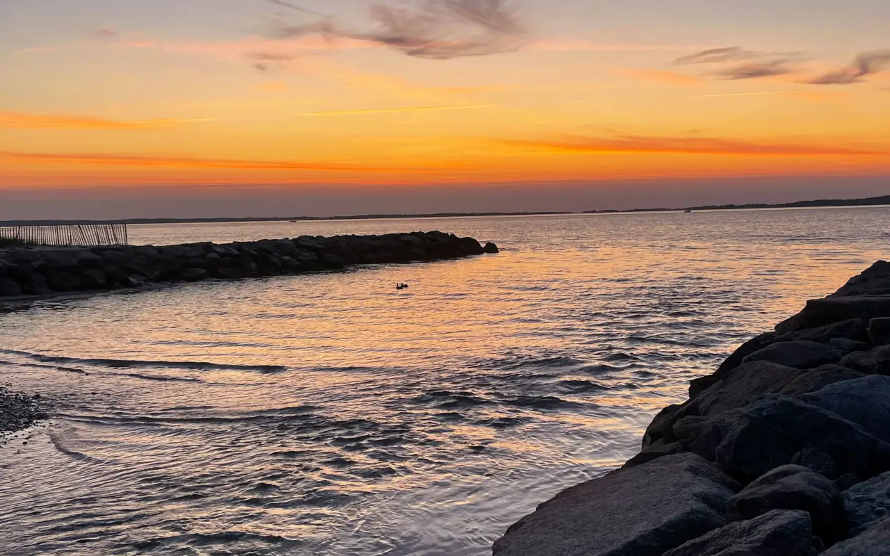 Sunset over Vineyard Sound from the West Chop shore with jetty rocks