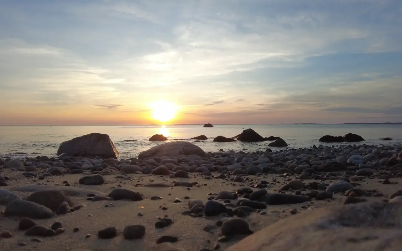 Boulders on a rocky West Tisbury beach with the sun setting over calm water