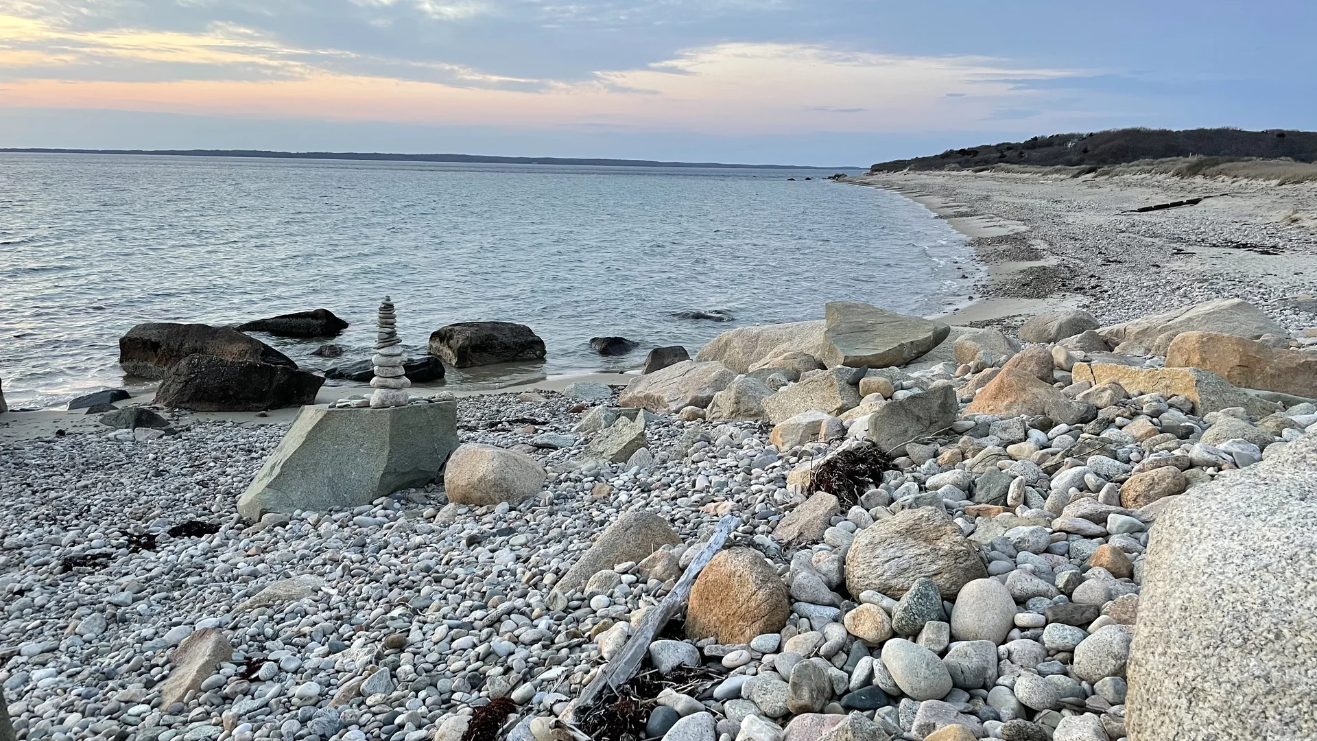 Cobblestones and a stone cairn at dusk on a West Tisbury beach